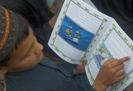 Boy in Pakistan reading the book the Magic Horse