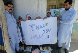 Girls and boys in the one-room schools run by HOPE in FATA with thank you sign