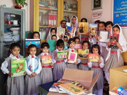 Girls in a classroom in Pakistan with books from a box library